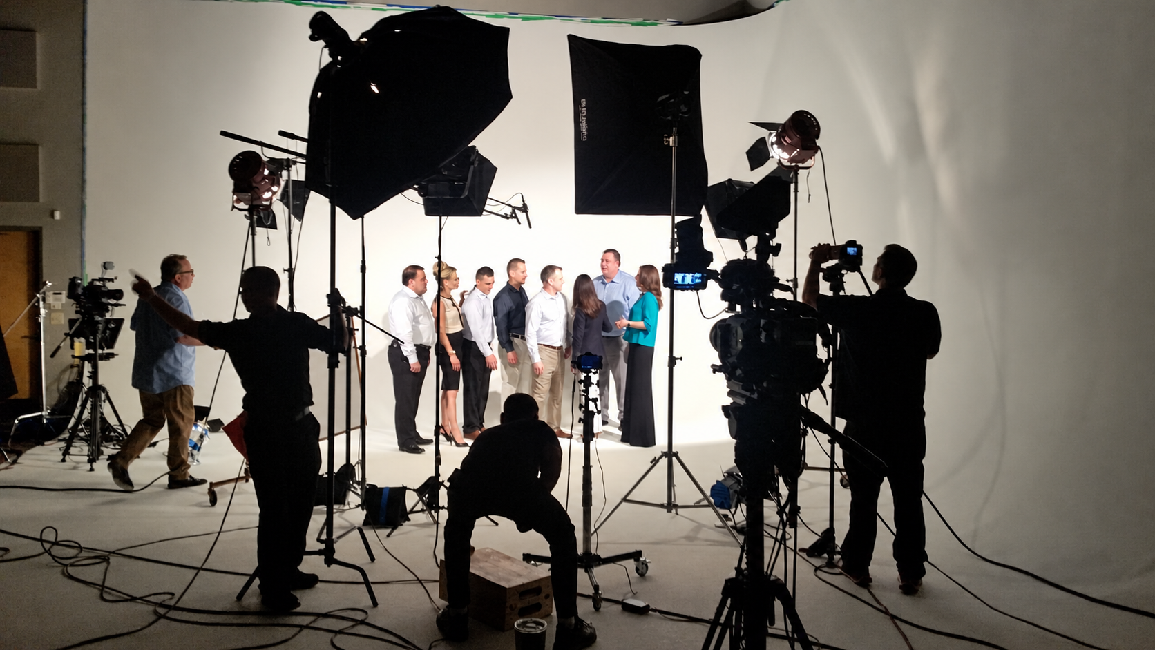 CineCut production crew filming a group on a white cyclorama stage